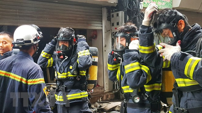 Các cán bộ chiến sỹ PCCC mặc trang bị bảo hộ để chuẩn bị tiếp cận hiện trường đám cháy. (Ảnh: Tuấn Anh/TTXVN)