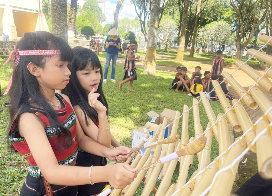 H'Srian đứng bên cạnh nhìn cháu gái HSrina chơi đàn T'rưng. Ảnh: Phương Dung H'Srian đứng bên cạnh nhìn cháu gái HSrina chơi đàn T'rưng. Ảnh: Phương Dung