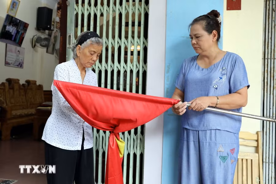 Bà Bạch Thị Khôi, cán bộ tiền khởi nghĩa ở phường Vĩnh Trại, thành phố Lạng Sơn, tỉnh Lạng Sơn cùng con gái treo cờ rủ để tưởng nhớ, tri ân Tổng Bí thư Nguyễn Phú Trọng. (Ảnh: Văn Đạt/TTXVN)