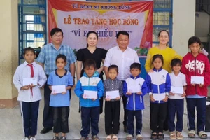 Thầy Vũ Văn Tùng (hàng sau, thứ 3 từ trái sang, người phụ trách "Tủ bánh mì 0 đồng") phối hợp với Ban Giám hiệu Trường Tiểu học và THCS Lê Văn Tám trao học bổng cho học sinh vượt khó học giỏi của trường. Ảnh: Văn Tùng