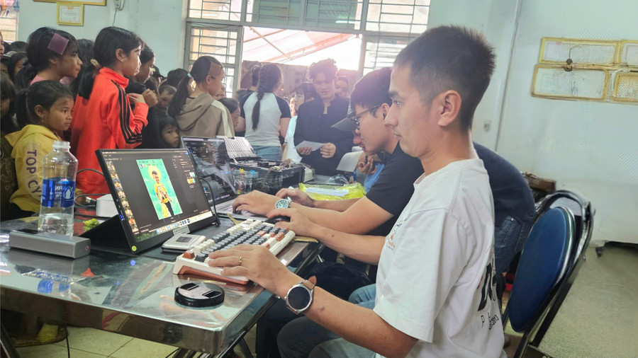 Anh Nguyễn Tấn Kần (bìa phải) cẩn thận chỉnh sửa từng bức ảnh của các em trước khi in và đưa vào khung. Ảnh: Ngọc Duy 20251006-173752.jpg