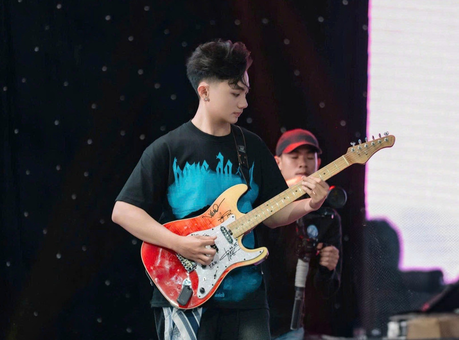 Em Hoàng Đức Tài (phường Pleiku, tỉnh Gia Lai) say mê biểu diễn guitar điện cùng ban nhạc trên sân khấu. Ảnh: NVCC 20250815-130028.jpg