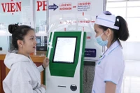 Nhân viên y tế Bệnh viện Nhi Gia Lai hướng dẫn người dân đăng ký khám chữa bệnh trên Kiosk y tế thông minh. Ảnh: HỒNG QUÝ