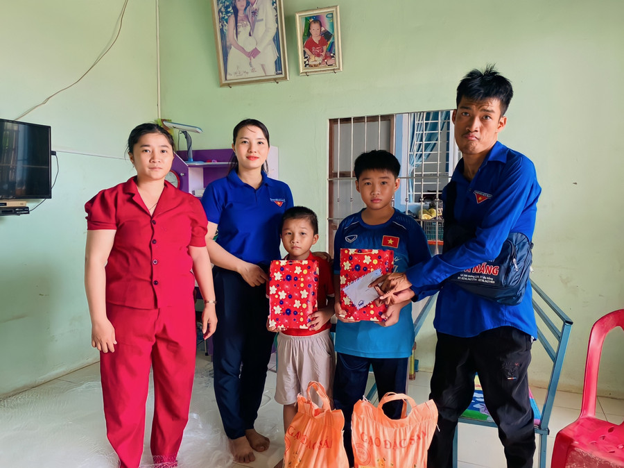 Dù di chuyển, nói chuyện khó khăn nhưng Hữu (bìa phải) vẫn cố gắng đến tận nhà thăm, tặng quà cho các trường hợp khó khăn. Ảnh: D.L 2.jpg