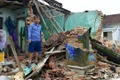 Người dân đứng trước đống đổ nát của ngôi nhà sau bão lũ.