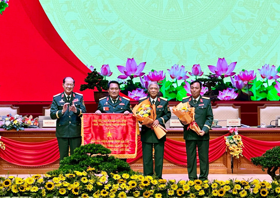 ທ່ານພົນເອກ ໂງຊວນລິກ, ຮອງປະທານຄະນະກຳມະການສູນກາງແນວໂຮມປະເທດຊາດຫວຽດນາມ, ປະທານສະມາຄົມນັກຮົບເກົ່າຫວຽດນາມ (ຊ້າຍ) ມອບທຸງຊົມເຊີຍໃຫ້ແກ່ສະມາຄົມນັກຮົບເກົ່າແຂວງ. ພາບ: T.K tang-co-thi-dua-cho-hoi-cuu-chien-binh.jpg