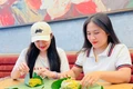 Chị Lê Thị Ni Na (bìa phải) gói xôi cốm cho khách hàng. Ảnh: M.K