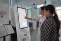 Nhân viên Bệnh viện Y học cổ truyền và Phục hồi chức năng Pleiku hướng dẫn người dân sử dụng kiosk y tế thông minh để đăng ký khám bệnh. Ảnh: Sơn Ca