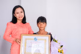 Bé Rơ Châm Thi (bìa phải) là con đỡ đầu của Hội LHPN xã Ia Din (huyện Đức Cơ) đạt thành tích xuất sắc trong học tập nhiều năm liền. Ảnh: Minh Châu