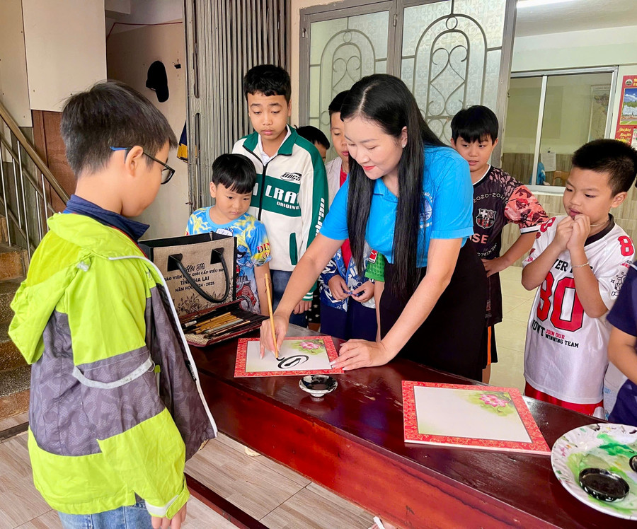 Thành viên Câu lạc bộ thư pháp hướng dẫn thiếu nhi cách viết thư pháp. Ảnh: Ngân Hoàng img-6278.jpg