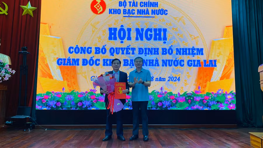 Phó Tổng Giám đốc KBNN Nguyễn Quang Vinh trao quyết định bổ nhiệm và chúc mừng ông Phạm Quang Bút-tân Giám đốc KBNN tỉnh Gia Lai. Ảnh: Sơn Ca