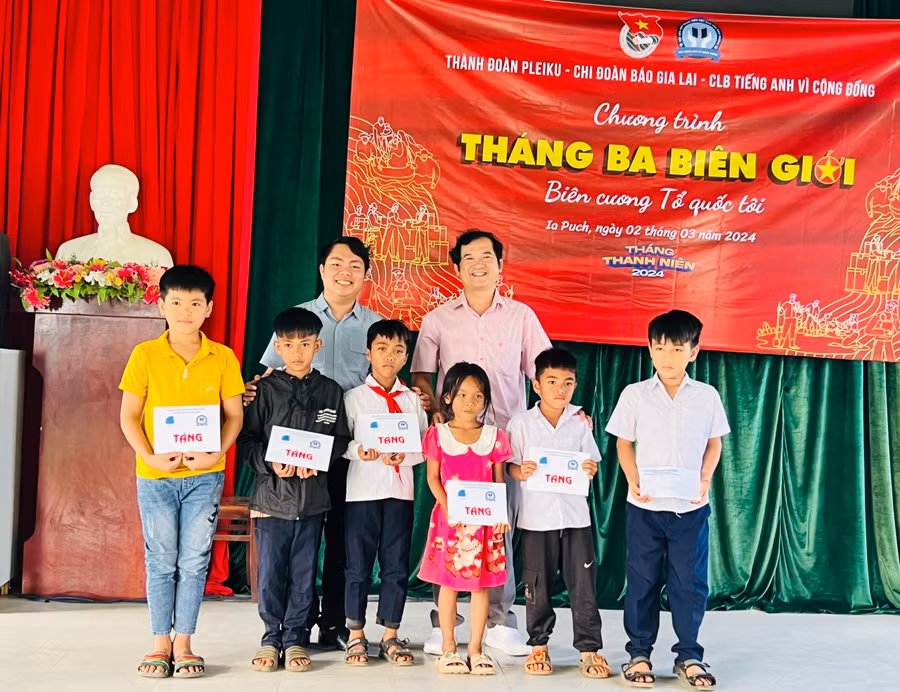 Phó Tổng Biên tập Đoàn Minh Dưỡng (hàng sau, bên phải) và anh Trương Chấn Sang-Chủ nhiệm Câu lạc bộ Tiếng Anh vì cộng đồng tỉnh Bình Dương tặng học bổng cho các em thiếu nhi khó khăn của xã Ia Púch. . Ảnh: P.L