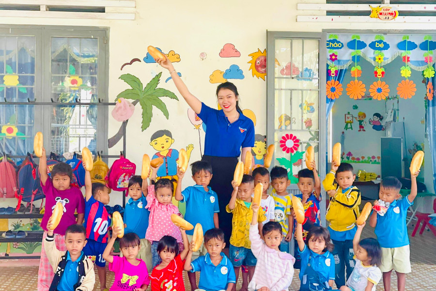 Chị Nay Thị Thu Hà-Phó Bí thư Chi Đoàn bôn Tơ Khế (xã Ia Tul, huyện Ia Pa) tặng bánh mì cho trẻ em bôn Tơ Khế. Ảnh: M.N