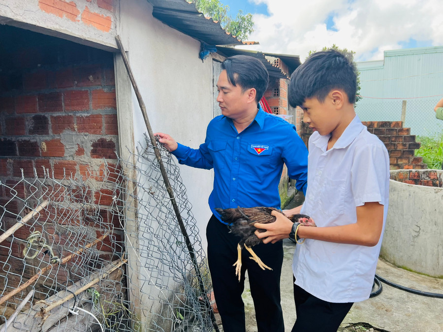 Anh Đỗ Duy Nam-Phó Bí thư Tỉnh Đoàn trao tặng đàn gà khăn quàng đỏ cho thiếu nhi khó khăn của xã Cửu An (thị xã An Khê). Ảnh: P.L