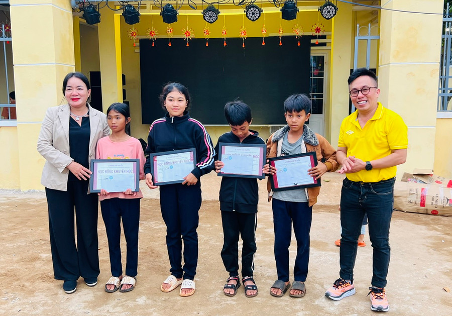 Chị Lý Thị Hồng Trị (bìa trái)-Trưởng ban Thường trực Mạng lưới tình nguyện Quốc gia khu vực Tây Nguyên và MC Hoàng Nam (bìa phải) tặng học bổng cho thiếu nhi vượt khó học giỏi. Ảnh M.N