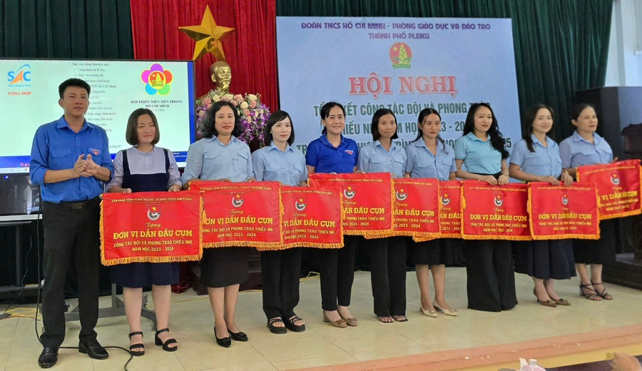 Anh Thái Giang Nam (bìa trái)-Bí thư Thành Đoàn Pleiku trao cờ thi đua cho các đơn vị dẫn đầu cụm thi đua công tác Đội năm học 2023-2024. Ảnh: M.N