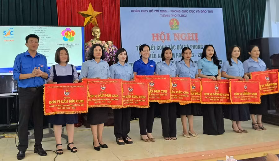 Anh Thái Giang Nam (bìa trái)-Bí thư Thành Đoàn Pleiku trao cờ thi đua cho các đơn vị dẫn đầu cụm thi đua công tác Đội năm học 2023-2024. Ảnh: M.N