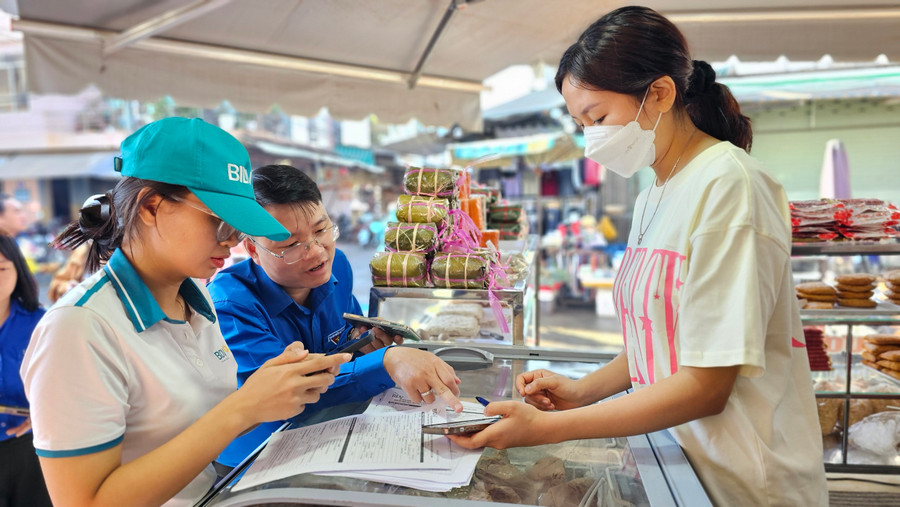 Ngân hàng BIDV chi nhánh Gia Lai hướng dẫn tiểu thương tại Trung tâm Thương mại TP. Pleiku sử dụng dịch vụ thanh toán không dùng tiền mặt. Ảnh: P.L Ngân hàng BIDV chi nhánh Gia Lai hướng dẫn tiểu thương tại Trung tâm Thương mại TP. Pleiku sử dụng dịch vụ thanh toán không dùng tiền mặt. Ảnh: P.L