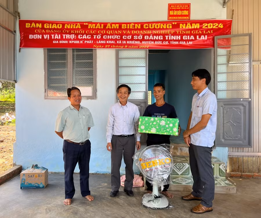 Phó Bí thư Đảng ủy Khối Huỳnh Tấn Đoan (thứ 2 từ trái sang) và Phó Chủ tịch UBND huyện Đức Cơ Siu Luynh (bìa phải) tặng quà ông Nay Luyn (ở giữa) tại lễ bàn giao "Mái ấm biên cương". Ảnh: M.N