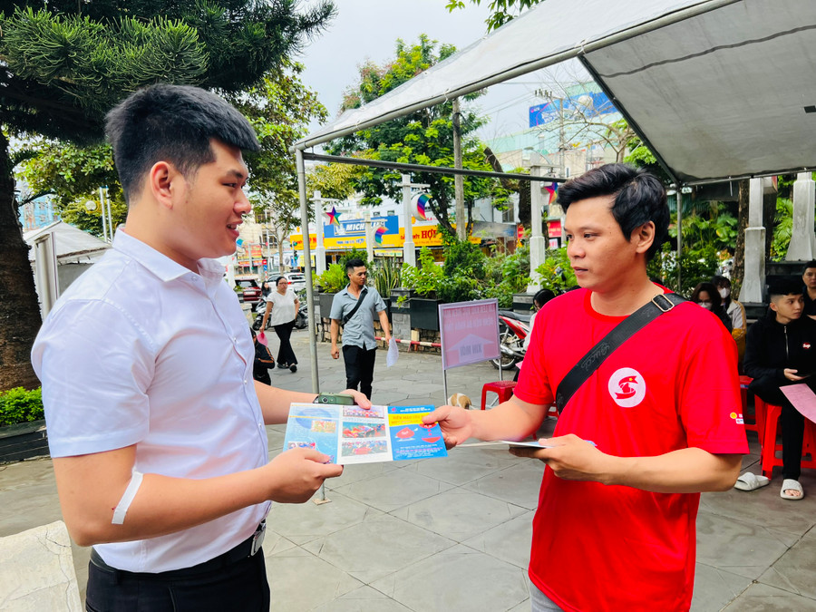 Anh Nguyễn Quốc Anh (bìa phải) phát tờ rơi tuyên truyền mọi người tham gia hiến máu tình nguyện. Ảnh: M.N