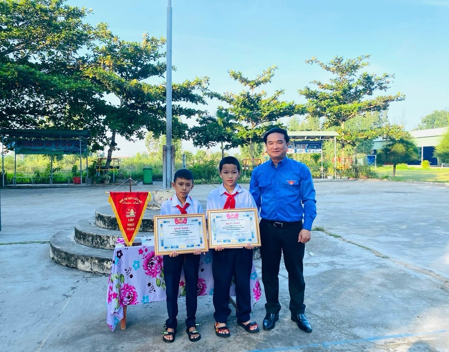 Anh Đỗ Duy Nam (bìa phải)-Phó Bí thư Tỉnh Đoàn tặng bằng khen gương người tốt-việc tốt cho 2 học sinh Trường Tiểu học Nguyễn Tất Thành. Ảnh: Trần Hoài
