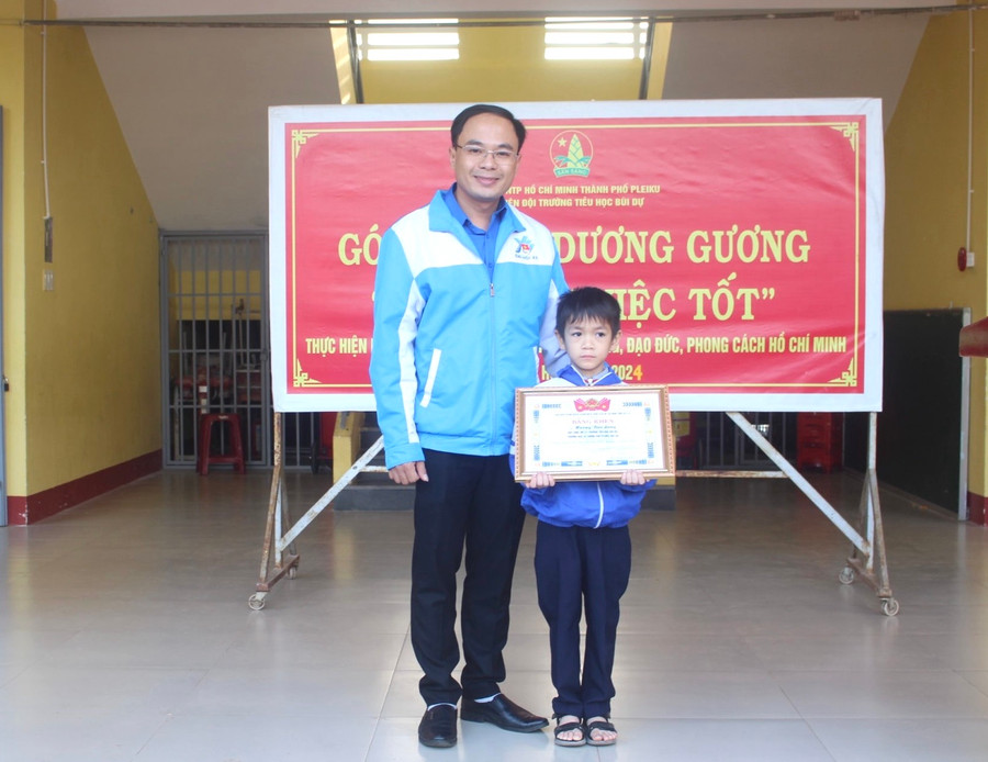 Anh Đỗ Đức Thanh (bìa trái)-Phó Bí thư Tỉnh Đoàn tặng bằng khen gương người tốt-việc tốt cho em Hoàng Bảo Long. Ảnh: P.L