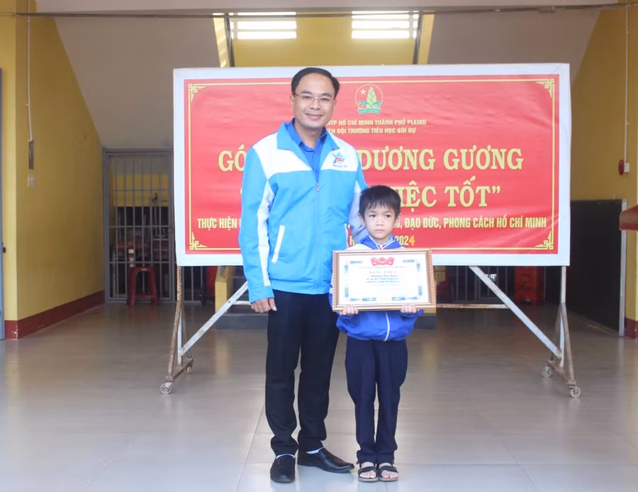 Anh Đỗ Đức Thanh (bìa trái)-Phó Bí thư Tỉnh Đoàn tặng bằng khen gương người tốt-việc tốt cho em Hoàng Bảo Long. Ảnh: P.L