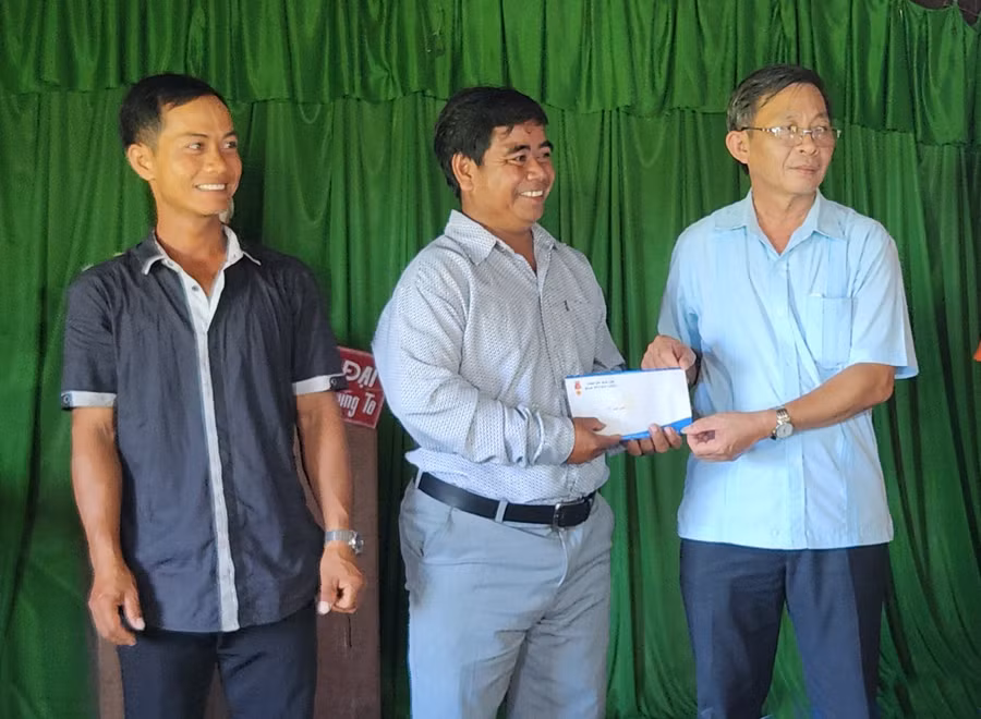 Trưởng ban Tuyên giáo Tỉnh ủy Huỳnh Thế Mạnh (bên phải) tặng 5 triệu đồng để hỗ trợ hộ nghèo làng Đê Chơ Gang mua bảo hiểm y tế. Ảnh: Ngọc Sang