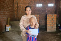 Chị Thơng (mẹ em Thạch) nhận tiền hỗ trợ do Báo Gia Lai và bạn đọc trao tặng. Ảnh: Ngọc Duy