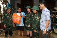 Thượng tướng Trương Thiên Tô (bìa trái) thăm, tặng quà người dân vùng lũ ở phường Quy Nhơn Đông.