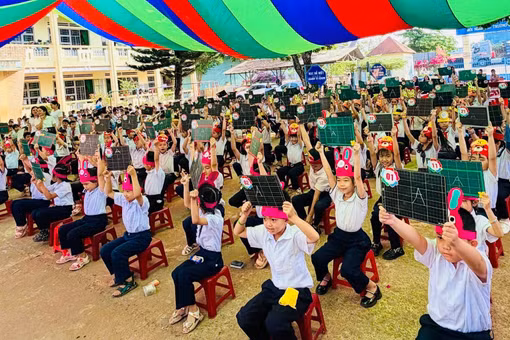Hơn 100 em học sinh ngồi trên sàn thi đấu giơ cao bảng trả lời câu hỏi bằng tiếng Anh tại hội thi Rung chuông vàng năm học 2025 - 2026 của Trường Tiểu học Nguyễn Du, xã Ia Tôr, tỉnh Gia Lai vào sáng 10-4