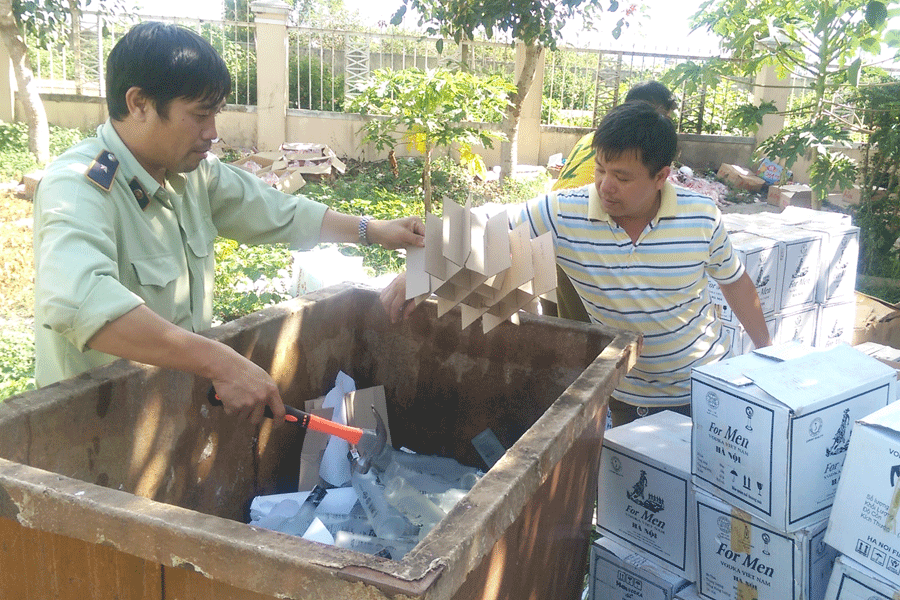 Lực lượng Quản lý Thị trường tổ chức tiêu hủy rượu giả. Ảnh: L.L Lực lượng Quản lý Thị trường tổ chức tiêu hủy rượu giả. Ảnh: L.L