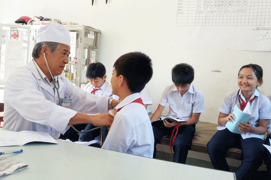 Bác sĩ Phạm Ngọc Thạch-Trưởng trạm Y tế phường Hội Thương thăm khám cho các em học sinh. Ảnh: N.N