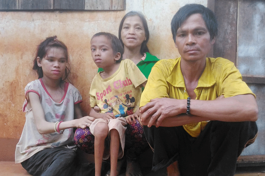 Vợ chồng anh Hoăt ngồi cạnh 2 đứa con bị nhiễm chất độc da cam. Ảnh: L.H.H