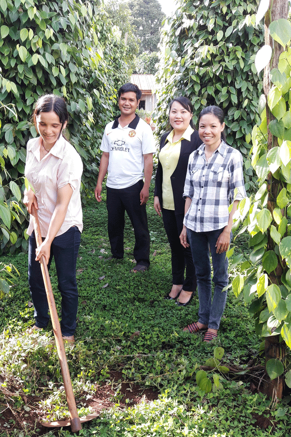 Chị Siu Một đang làm cỏ vườn tiêu cùng cán bộ công đoàn công ty. Ảnh: Đ.Y
