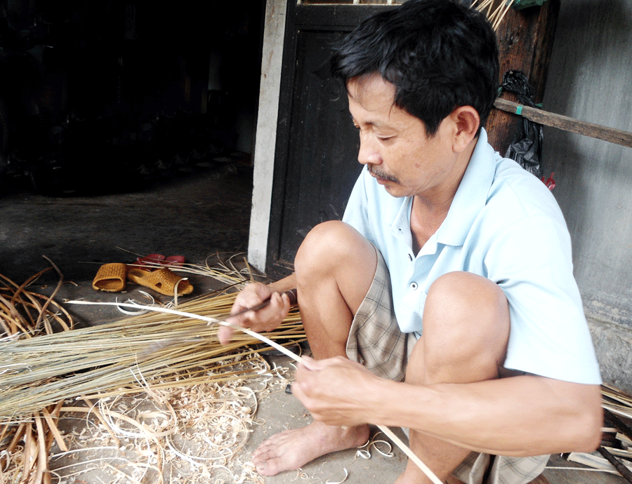 Ông Phạm Quốc tỉ mỉ vót từng cọng mây bó chổi. Ảnh: N.M