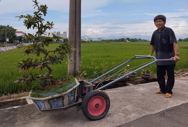 Ông Nguyễn Đình Thái và chiếc xe càng để gắp - vận chuyển chậu hoa. Ảnh: XUÂN VINH