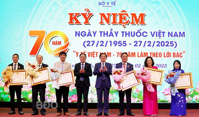 Thừa ủy quyền của Chủ tịch nước, Bí thư Tỉnh ủy Hồ Quốc Dũng (thứ 4 từ phải sang) trao quyết định của Chủ tịch nước cho 7 Thầy thuốc Ưu tú; Chủ tịch UBND tỉnh Phạm Anh Tuấn (thứ 5 từ phải sang) tặng hoa chúc mừng các Thầy thuốc Ưu tú. Ảnh: M.H