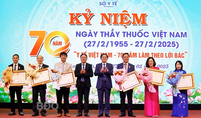 Thừa ủy quyền của Chủ tịch nước, Bí thư Tỉnh ủy Hồ Quốc Dũng (thứ 4 từ phải sang) trao quyết định của Chủ tịch nước cho 7 Thầy thuốc Ưu tú; Chủ tịch UBND tỉnh Phạm Anh Tuấn (thứ 5 từ phải sang) tặng hoa chúc mừng các Thầy thuốc Ưu tú. Ảnh: M.H