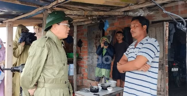 Chủ tịch UBND Phạm Anh Tuấn trò chuyện với một người nuôi tôm ven biển, căn dặn người dân phải chủ động bảo vệ an toàn tính mạng và tài sản. Ảnh: T.S