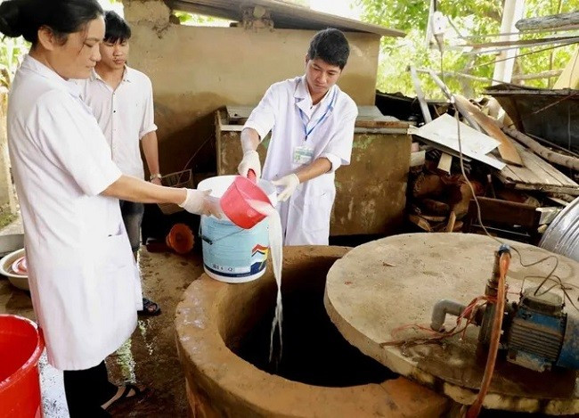 Nhân viên y tế tiến hành vệ sinh giếng nước sinh hoạt cho người dân tại vùng ngập lụt.