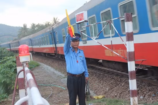 An toàn cho mỗi chuyến tàu và người tham gia giao thông đường bộ là trách nhiệm và cũng là niềm vui của nhân viên gác chắn. - Trong ảnh: Nhân viên gác chắn Km 1017+450 Đặng Thời đón tàu qua đường ngang.