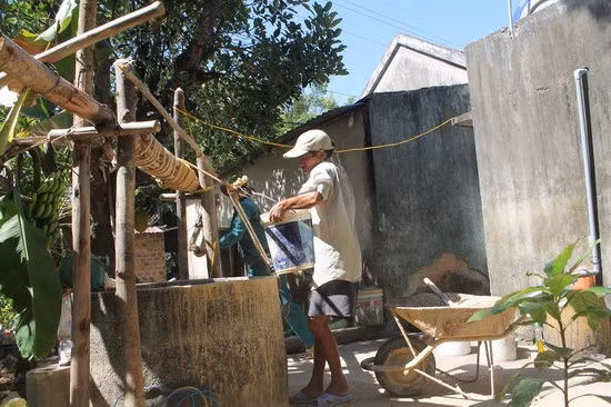 Thợ đào giếng sợ nhất là người quay xô để đưa đất, cát lên xuống giếng không chú ý, để đất đá rơi xuống, làm chấn thương người đào giếng. - Trong ảnh: Nhóm thợ đào giếng cẩn thận đưa xô cát xuống lòng giếng để lắp bộng giếng.