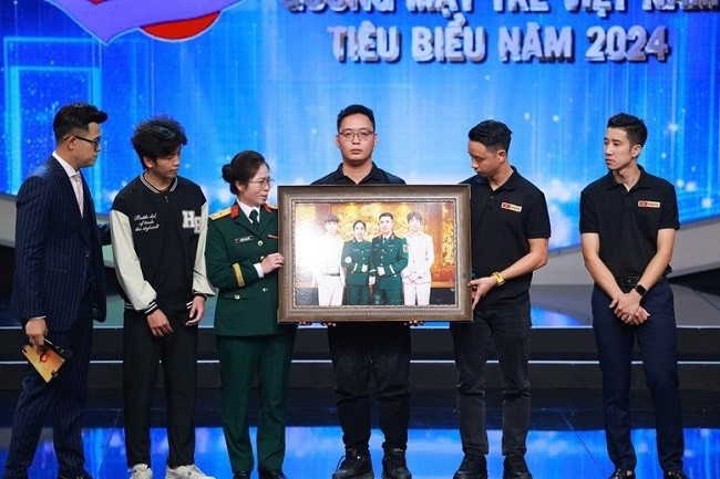 Phùng Quang Trung, Gương mặt trẻ Việt Nam tiêu biểu năm 2024 và Nhóm phục dựng ảnh Skyline trao lại bức ảnh phục dựng cho gia đình liệt sĩ Tăng Bá Hưng tại chương trình. Ảnh: VGP/Nhật Bắc