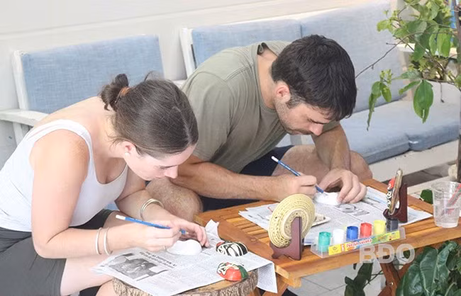 Du khách nước ngoài thích thú trải nghiệm hoạt động vẽ mặt nạ hát bội. Ảnh: TRẦN NGỌC VÂN