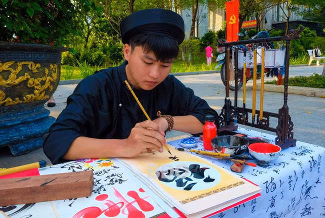 “Ông đồ” trẻ Lê Thanh Trung, ở xã Phước Hưng (huyện Tuy Phước) hiện đang là sinh viên năm 2, khoa Tài chính - Ngân hàng Trường ĐH Quy Nhơn viết thư pháp Việt và cả chữ Hán rất thuần thục. Ảnh: NGỌC NHUẬN