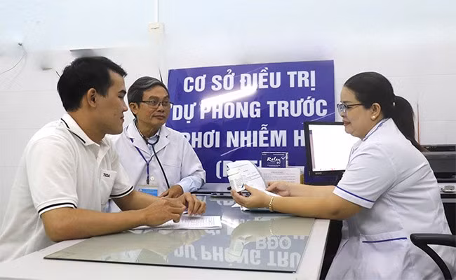 Anh Lê Văn Linh (bìa trái) nhận thuốc điều trị PrEP tại phòng khám điều trị chương trình thuộc Trung tâm Kiểm soát bệnh tật. Ảnh: M.H