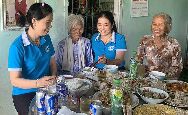 Mẹ Tám (thứ 2 từ trái sang) bên mâm cơm do các chị em phụ nữ xã Nhơn Tân (TX An Nhơn) tự tay chuẩn bị. Ảnh: D.NGỌC Mẹ Tám (thứ 2 từ trái sang) bên mâm cơm do các chị em phụ nữ xã Nhơn Tân (TX An Nhơn) tự tay chuẩn bị. Ảnh: D.NGỌC