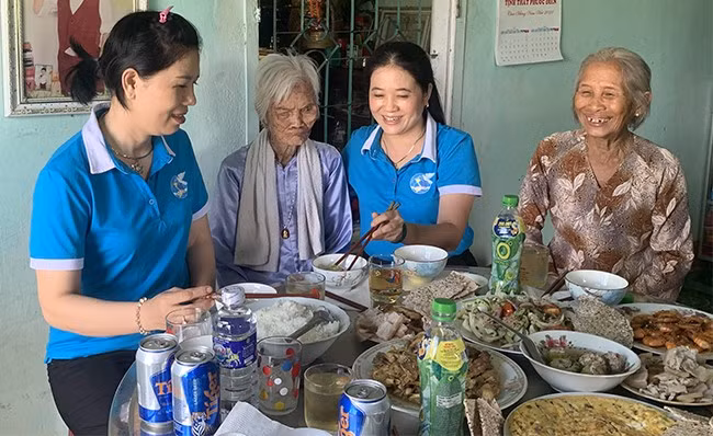 Mẹ Tám (thứ 2 từ trái sang) bên mâm cơm do các chị em phụ nữ xã Nhơn Tân (TX An Nhơn) tự tay chuẩn bị. Ảnh: D.NGỌC