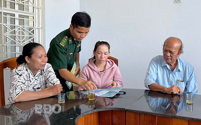 Cán bộ đồn Biên phòng Mỹ An phát tờ rơi tuyên truyền cho ngư dân.